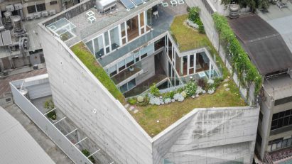 Aerial view of an angular concrete home with a central courtyard and green roof