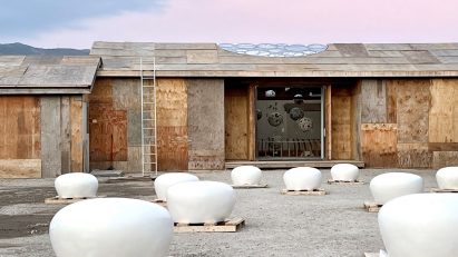 A plywood building on a construction site with white domes in front