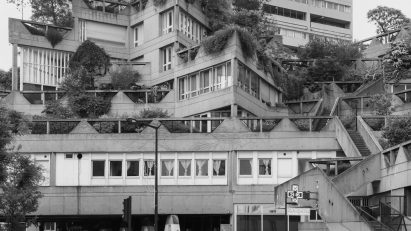 Black and white photo of a brutalist residential and commercial building complex with blocks aligned at different angles