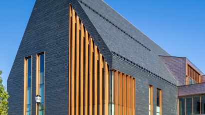 Slate-clad building with a steep-pitched roof and wood louvres