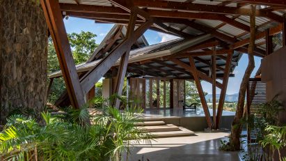 Paved terrace in a residential garden with an angular metal roof supported by a wooden structure
