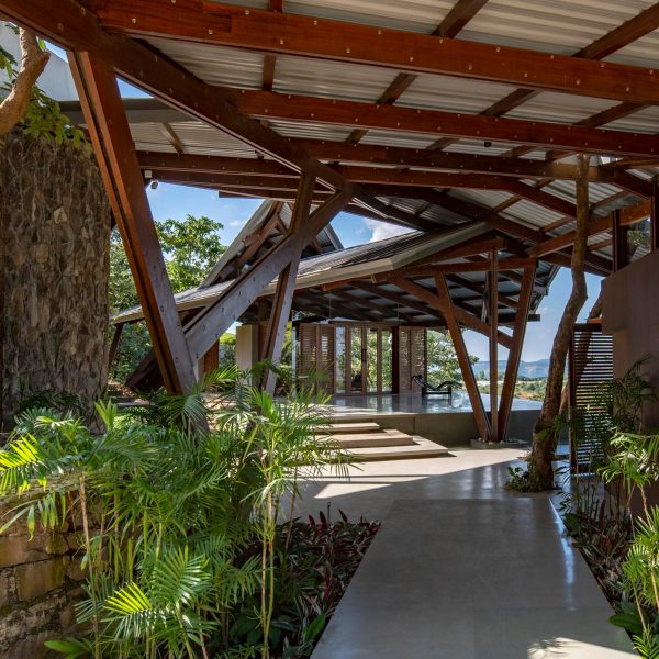 Paved terrace in a residential garden with an angular metal roof supported by a wooden structure