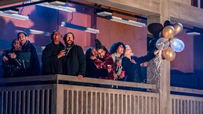Actors standing on a balcony that replicates the Park Hill estate