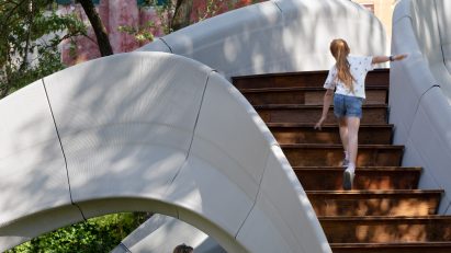 Girl climbing up stairs of Striatus 3D-printed concrete footbridge