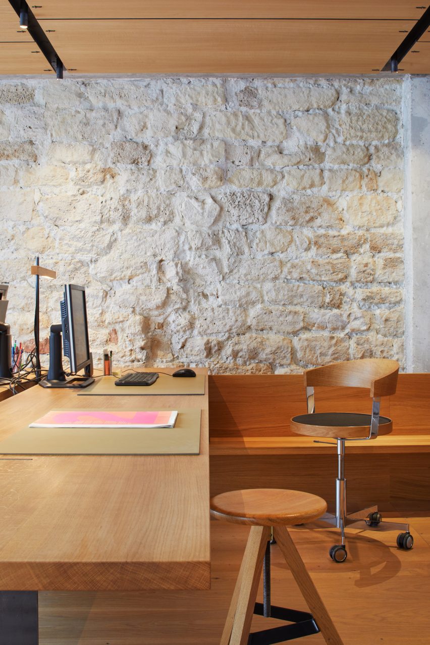Wooden desk and swivel chairs next to a white brick wall