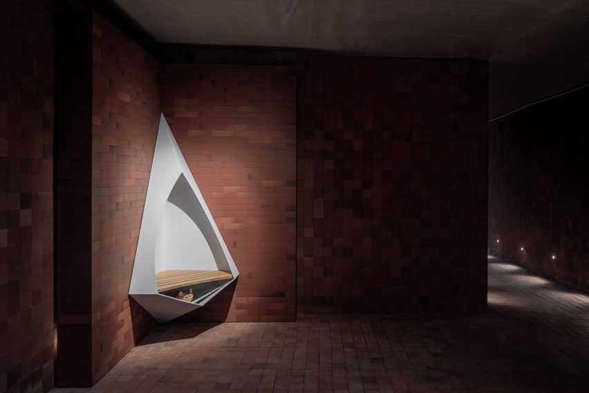 Lit corner of brick corridor with triangular seat inserted