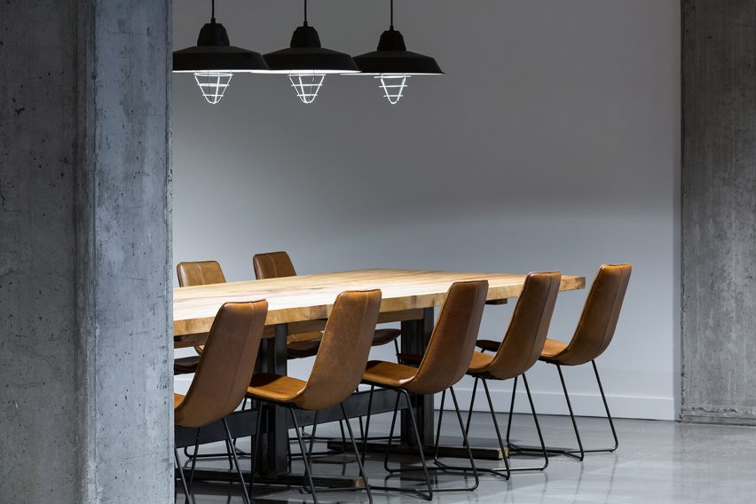 Office meeting room with concrete walls and floor and a large wood table with brown chairs