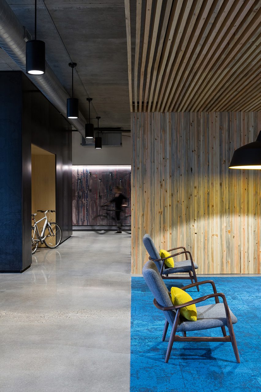 An interior space with concrete flooring and timber batons covering the wall and ceiling of a seating area