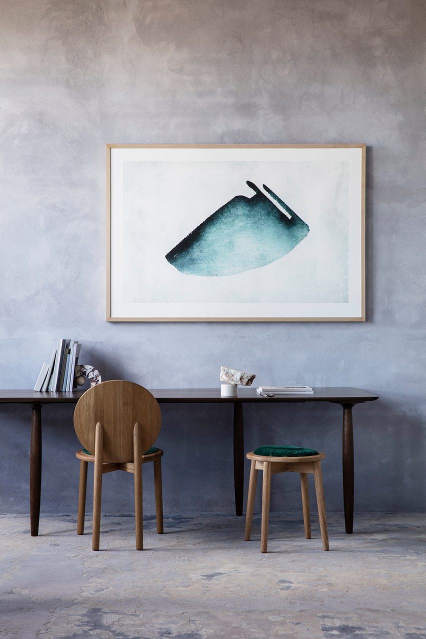 A circular wooden chair and stool at a desk in a concrete room
