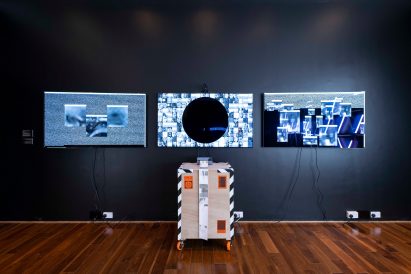 Assembly of three screens mounted on dark wall