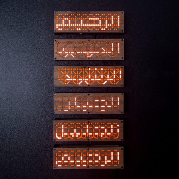 Six wooden panels mounted on dark wall with lit up Arabic text on each