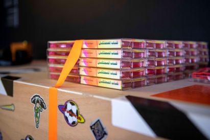 Photograph showing piles of casette tapes on table covered in stickers