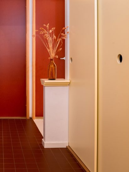 Cream sliding doors and red accents within apartment by Westblom Krasse Arkitektkontor