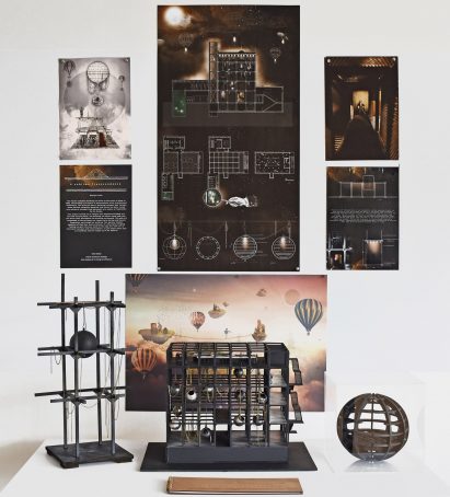 A photograph of a display that includes a model and print-outs with technical drawings