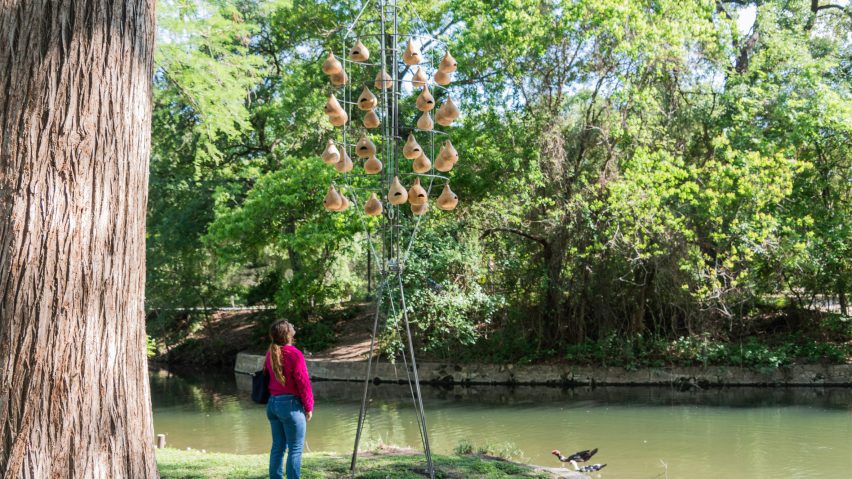 A series of bird boxes on a wire structure in a park by a lake