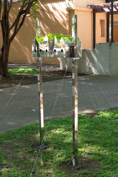 A birdhouse with a series of pitched roofs and reflective surfaces