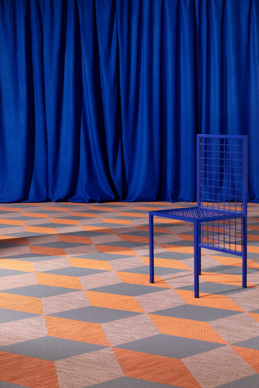 Orange and grey carpet tiles with a blue chair and curtains