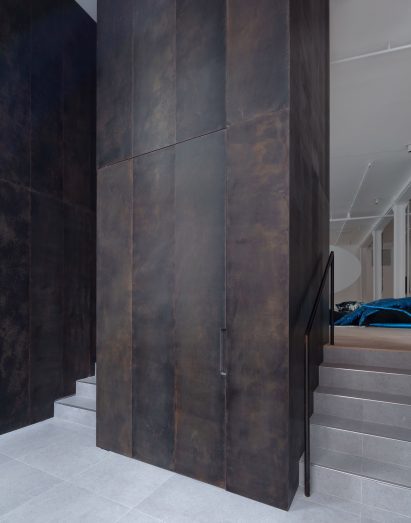 Patinated bronze panels line the entry threshold