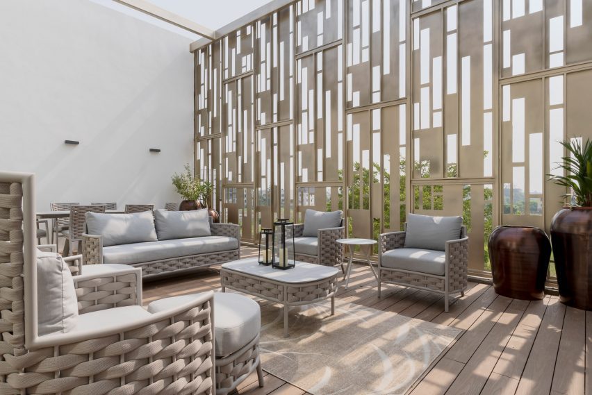 Outdoor terrace with sofas, lounge chairs and a perforated metal scree