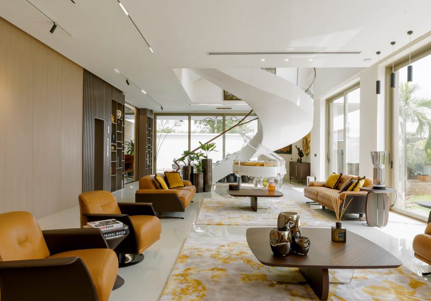 Interior living space with a wood coffe table, orange lounge chairs, large rugs and a white spiral staircase