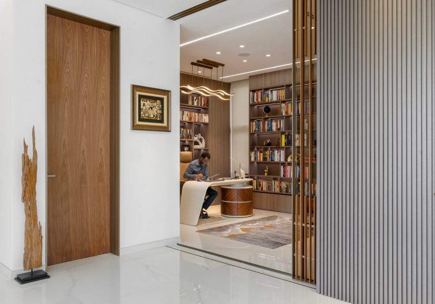Interior space with white walls, glossy white floors, wooden door and a office desk