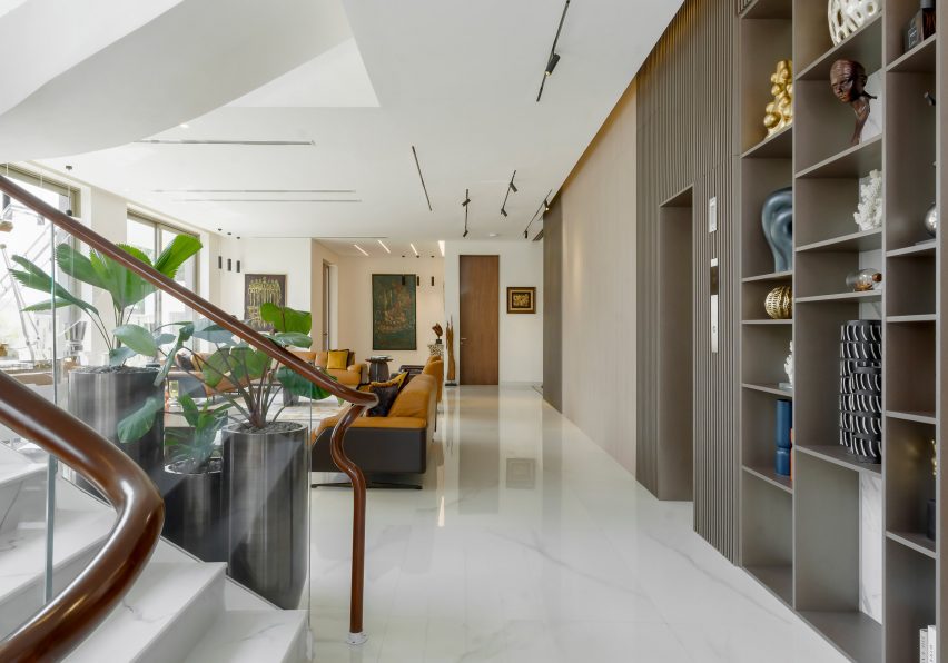 Open-plan living space with white glossy floor, built-in wall storage and orange lounge chairs