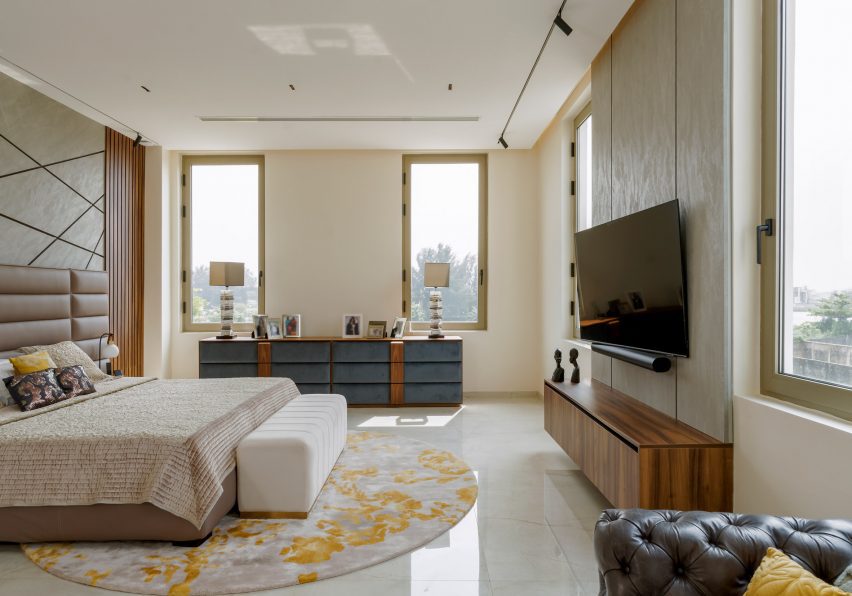 A bedroom with glossy cream floors, wall-hung TV, wooden console and a double bed