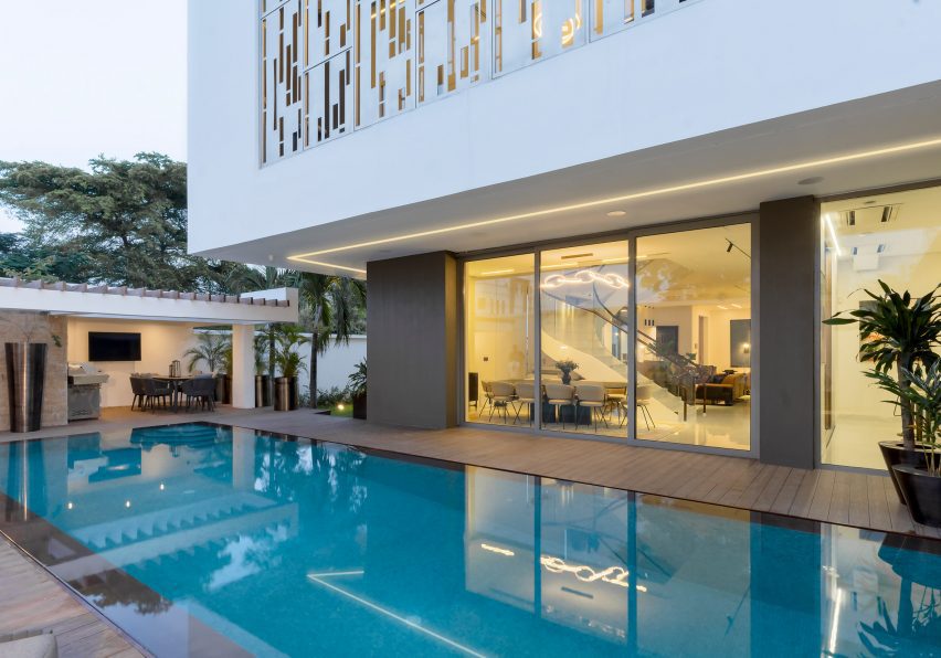 Exterior of a white and grey luxury home with a blue swimming pool by CmDesign Atelier