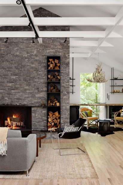 Stone fireplace with modern chairs and an antler chandelier