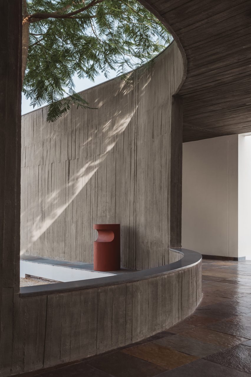 A covered walkway with concrete walls and openings overlooking a courtyard
