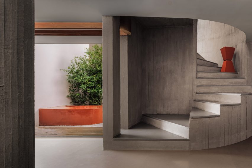A concrete room with a curving concrete staircase