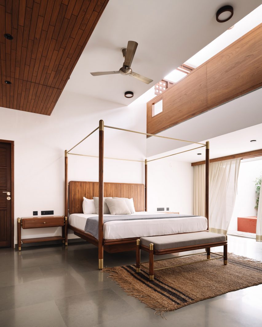 Bedroom with polished concrete floors, white walls and a wooden four-poster bed