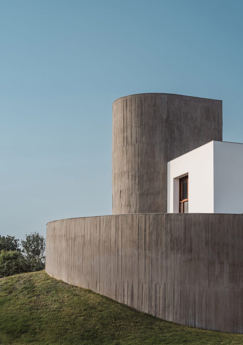Concrete house on a grass mound with a curved exterior wall