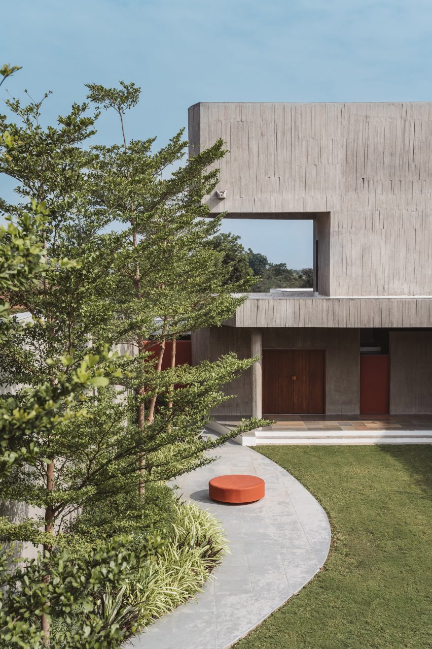 Grass garden in front of a concrete home with a winding path