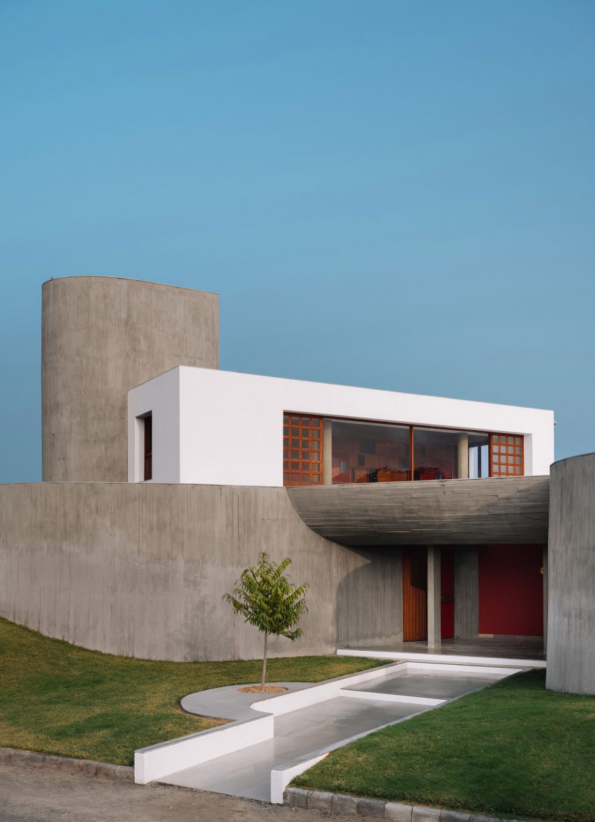 Entrance to the concrete Enclosure house by Design Ni Dukan with concrete canopy and grass lawn