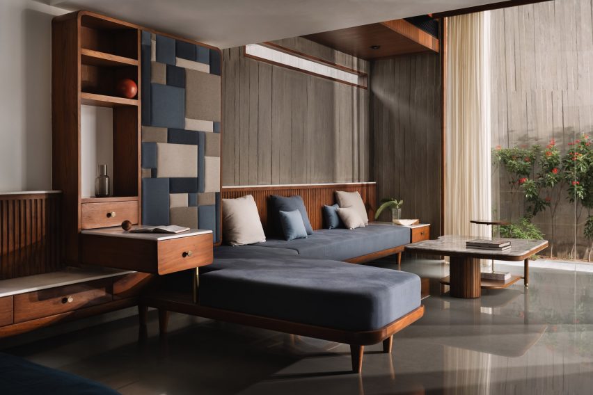 A living room with concrete walls and floors, wood furniture and an L-shaped sofa