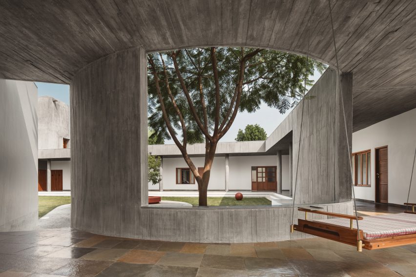 Covered concrete walkway with a swing seat and an opening in the wall that overlooks an outdoor courtyard