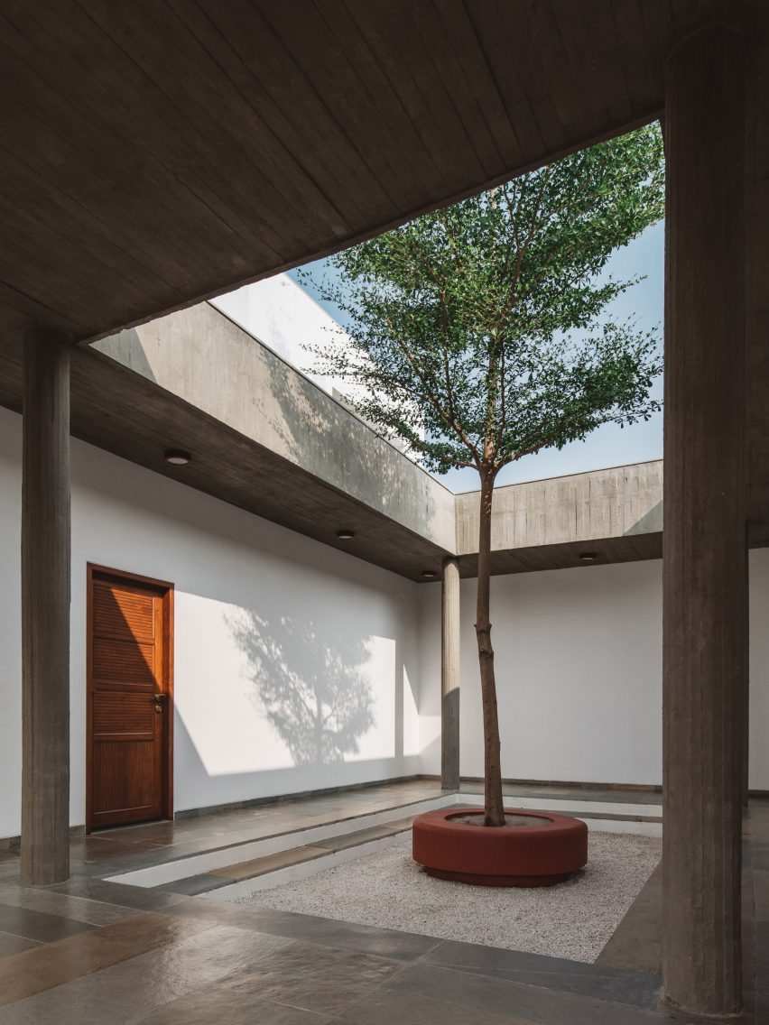 A courtyard with a surrounding concrete structure and a central tree
