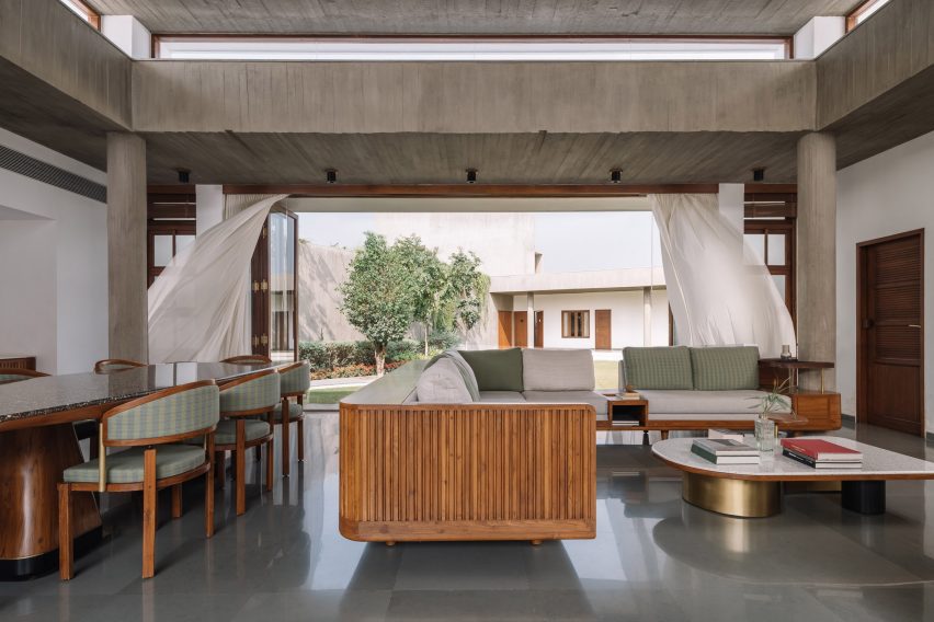 Open-plan living and dining space with concrete structure and a large opening leading to a courtyard