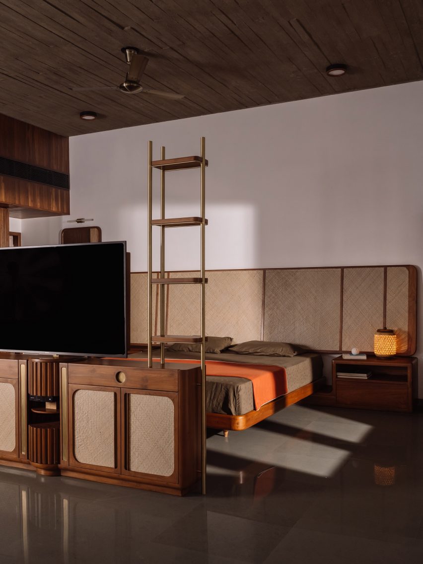 A bedroom with wood-panelled walls, concrete floors and a red throw over the bed