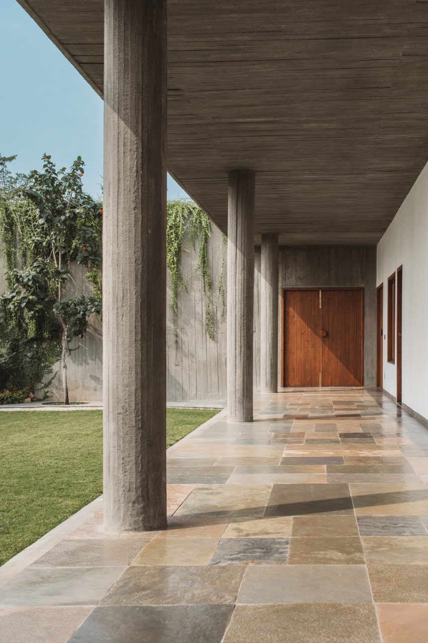 A covered outdoor walkway next to a courtyard with concrete columns