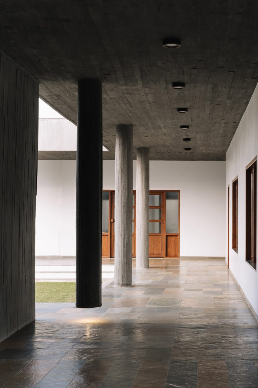 A covered outdoor walkway next to a courtyard with concrete columns