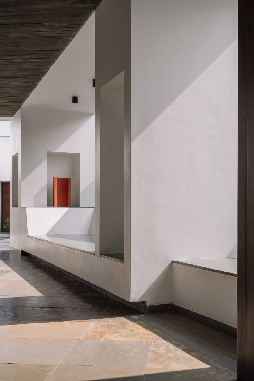 Concrete walkway with white walls and seating built into openings