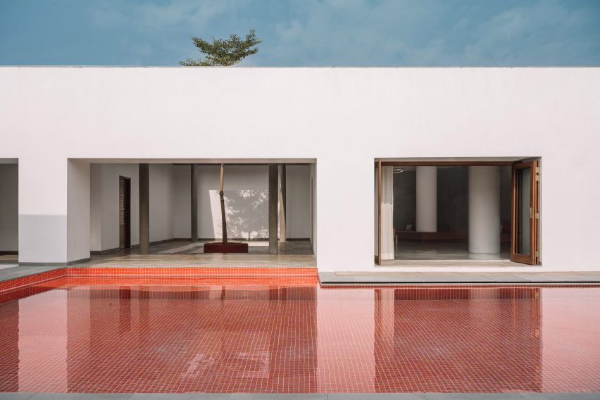 Outdoor swimming pool with red tiles next to a white house