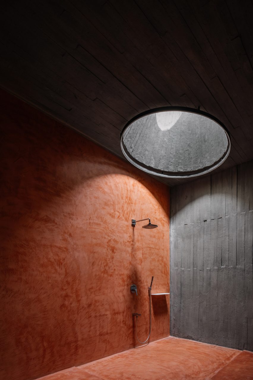 Wet room with red and grey concrete walls and circular skylight