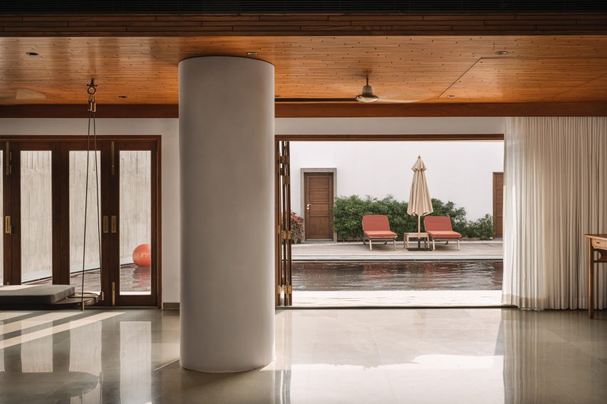 Interior space with polished concrete floors, round concrete column and an opening leading to a swimming pool