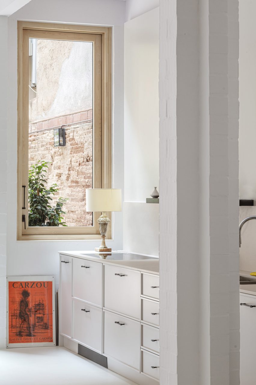 Kitchen with white cabinets, white floors, white walls and a wood-framed window