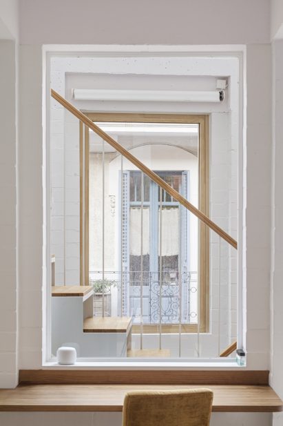 White interior of House 1616 with a square opening revealing a staircase and a window beyond