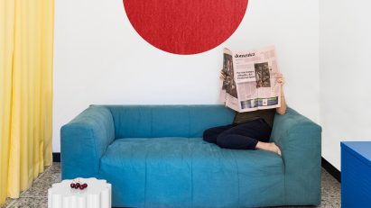 Living room with blue sofa, yellow curtain and red circular wall hanging