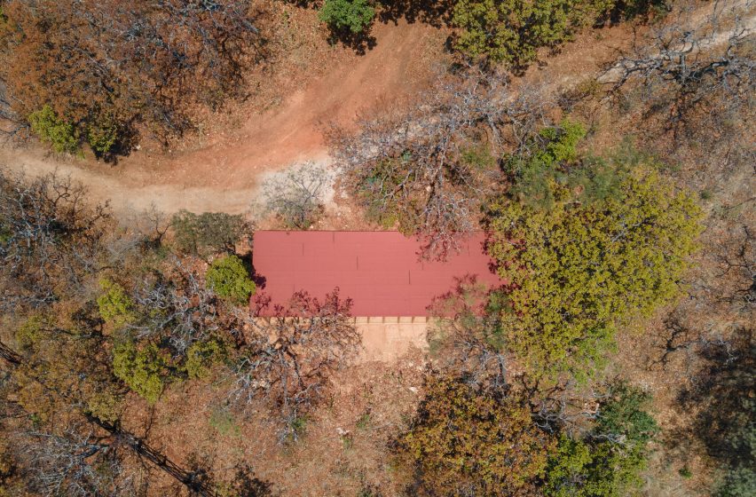 Aerial view of a home with a red roof on a sandy hill in Mexico with trees